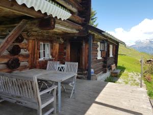 una terrazza in legno con tavolo e sedie su una cabina di Rütland a Fideris Dorf