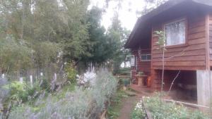 a log cabin with a garden in front of it at Cabañas Huilipan Gonzalez in Nueva Imperial