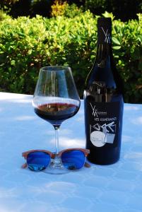 a glass of wine with sunglasses next to a bottle of wine at Le Clos Saint André in Banyuls-sur-Mer