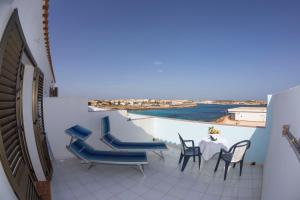 a balcony with chairs and a table with a view of the ocean at Hotel Giglio in Lampedusa