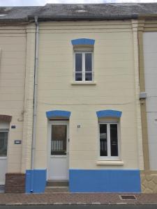 une maison jaune avec des parures bleues et deux fenêtres dans l'établissement La Bethencouroise, à Béthencourt-sur-Mer