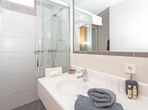 un bagno bianco con lavandino e doccia di Wiesenhof, Hotel direkt am See a Weissensee
