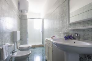 a white bathroom with a sink and a toilet at Attico Saker in Racale