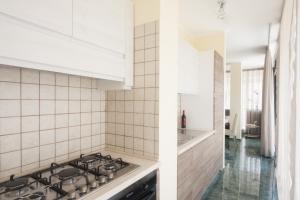a kitchen with white tiled walls and a stove top oven at Attico Saker in Racale