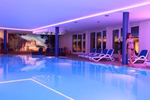 a woman standing next to a swimming pool in a hotel at Hotel Belle Vue in Vianden