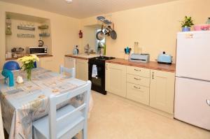 een keuken met een tafel en een witte koelkast bij Cottage 312 - Ballyconneely in Ballyconneely