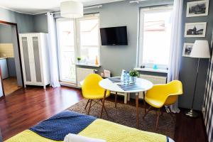 a living room with a table and yellow chairs at Apartamenty Centrum in Koszalin