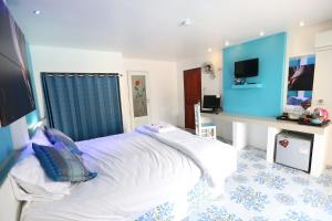 a bedroom with a large white bed and a desk at The Orchid Resort & Relax in Maha Sarakham