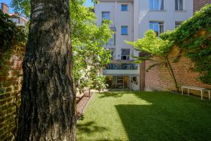 Ein Baum in einem Hof mit einem Gebäude im Hintergrund in der Unterkunft 1bd apartment with garden Brugmann area in Brüssel