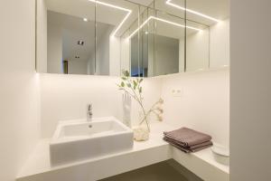 a white bathroom with a sink and a mirror at 1bd apartment with garden Brugmann area in Brussels +18 photos
