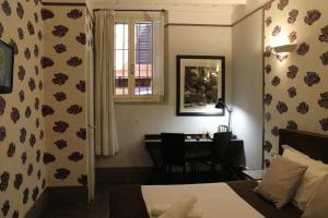 a bedroom with a bed and a desk and a window at Locanda degli Antiquari in Rome