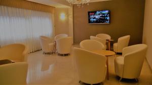 Habitación con sillas blancas y TV en la pared. en Hotel Miramar 2** Superior, en A Lanzada