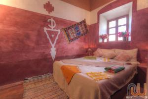 a bedroom with a bed with a cross on the wall at Guest housse Kasbah tifaoute in Aït Benhaddou