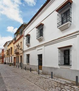 a white building with barred windows on a street at Triana House in Seville
