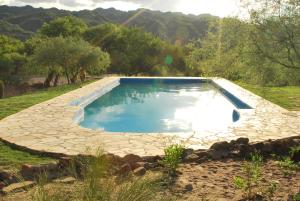 a swimming pool in a yard with a stone path around it at Finca Puesta del sol in San Agustín de Valle Fértil