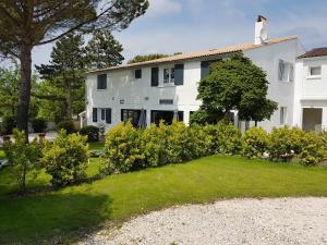una casa blanca con un patio con arbustos en Le lodge, en Vaux-sur-Mer