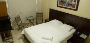 1 dormitorio con 1 cama, mesa y sillas en Rivera del Rio Hotel, en Piura