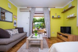 een woonkamer met een bank en een tv bij Madonna Guest House in Dubrovnik