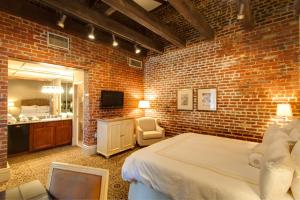 een slaapkamer met bakstenen muren, een bed en een spiegel bij Dauphine Orleans Hotel in New Orleans