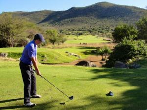 a man is playing golf on a golf course at Waterberg INN in Modimolle