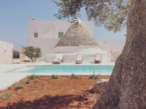 a swimming pool with two chairs and a building at Masseria Fenicia in Monopoli