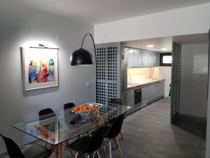 uma cozinha e sala de jantar com uma mesa de vidro e cadeiras em By the Beach em Almancil