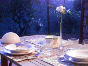 a wooden table with plates and glasses and a flower at Dèpendance Argentario in Porto Santo Stefano