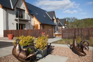a garden with two large bronze roosters in front of a house at Tower Ridge Apartments in Fort William