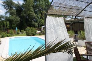 een zwembad met een witte luifel en een stoel ernaast bij Chambres d´Hôtes Belle Rivière in Salernes