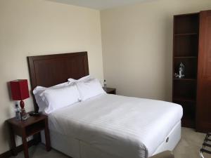 a bedroom with a large white bed and a night stand at Beaumont House in Beaumont