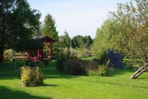 a garden with a red building and some flowers at Atelier Galerie Anne Drouin Peinture & Pension in Sainte-Julie