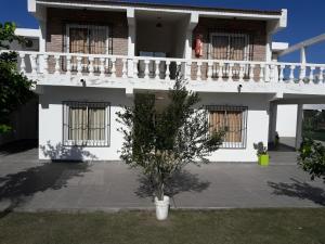 Una casa blanca con un árbol delante. en Apart Ma & Cris II en Termas de Río Hondo