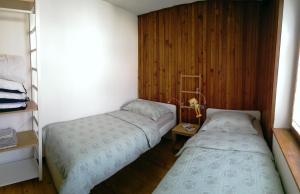 a bedroom with two beds and a wooden wall at Hiša Kala in Kobarid