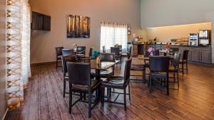 a dining room with tables and chairs and a kitchen at Best Western Butner Creedmoor Inn in Creedmoor