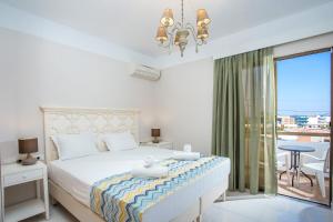 a white bedroom with a bed and a balcony at Voula Studios in Faliraki