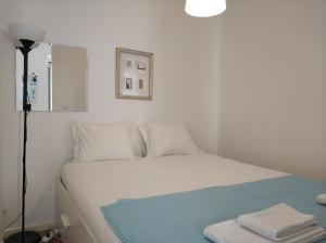 1 dormitorio con cama blanca y manta azul en Alcantara Quiet & Calm in Lisbon, en Lisboa