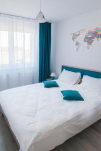 a large white bed with blue pillows on it at Friendly Rentals Brasov in Braşov