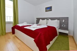 sypialnia z dużym łóżkiem i czerwonym kocem w obiekcie Apartmani Astrado Petrčane w Petrčane