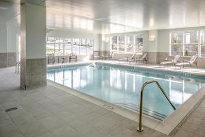 a large swimming pool in a building with tables and chairs at Hotel Madison & Shenandoah Conference Ctr. in Harrisonburg