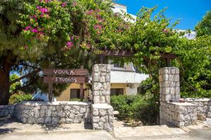 a sign in front of a building with pink flowers at Voula Studios in Faliraki