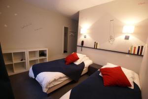 a bedroom with two beds with red pillows at Hotel de la Placette Barcelonnette in Barcelonnette