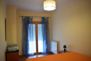 um quarto com uma cama e uma janela com cortinas azuis em T2 | Galeões | Nazaré na Nazaré