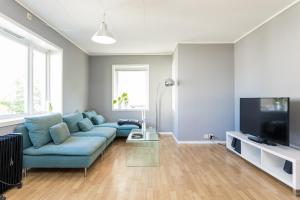 a living room with a blue couch and a flat screen tv at Grand Villa Stavanger in Stavanger