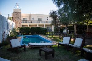 a backyard with a swimming pool and chairs and a building at Luna Serrana Hotel in Capilla del Monte