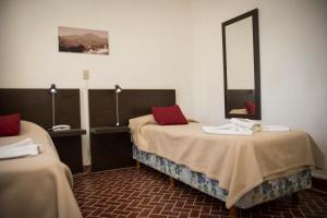 Habitación con 2 camas y espejo. en Luna Serrana Hotel en Capilla del Monte