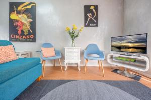 a living room with a couch and two chairs and a tv at Chic East Sydney Pad in Sydney