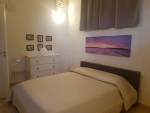 een slaapkamer met een bed en een schilderij aan de muur bij Casa Anna in Specchia