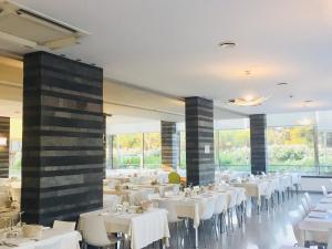 un restaurante con mesas y sillas blancas y ventanas en Hotel Corfù, en Pineto