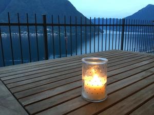a candle in a cup sitting on a wooden table at Colonno Panoramica Lago Di Como in Colonno