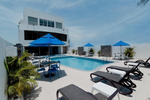 - une piscine avec des chaises et des parasols à côté d'un bâtiment dans l'établissement Howard Johnson by Wyndham Barranquilla Versalles, à Barranquilla
